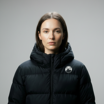 Person wearing a black puffer jacket with a logo on a gray background